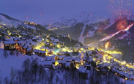 Night time view of ski resort chalets and exploding fireworks