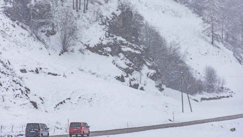 2 vans in snow driving away from camera