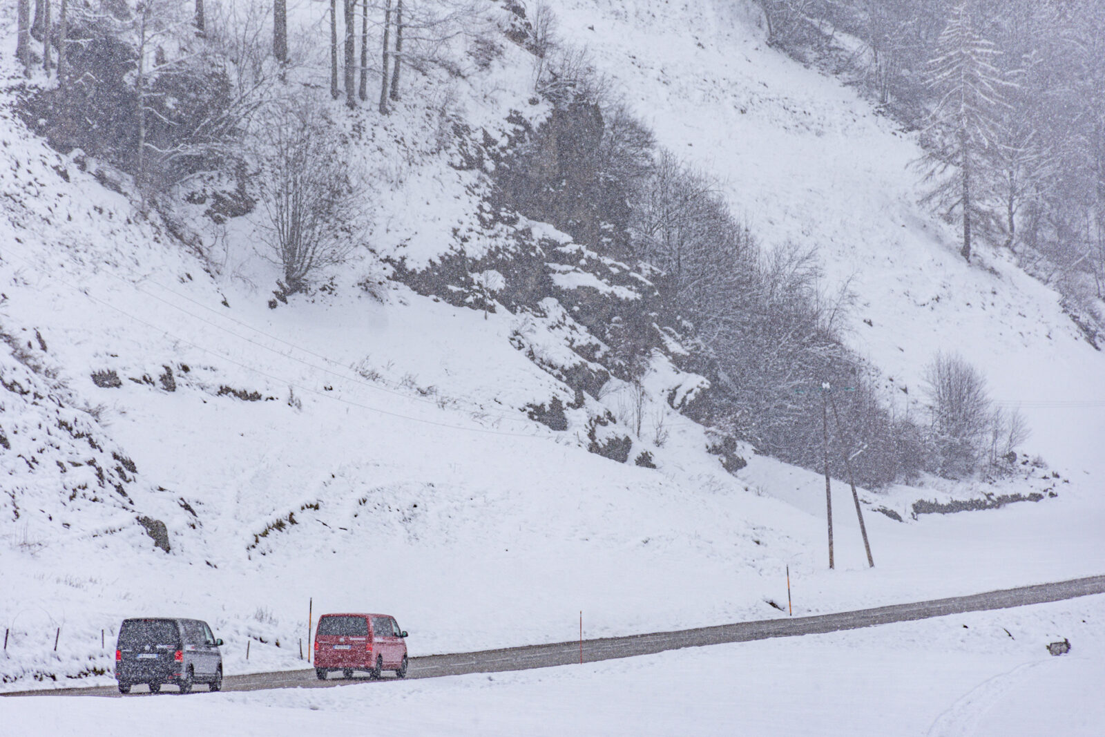 2 vans in snow driving away from camera