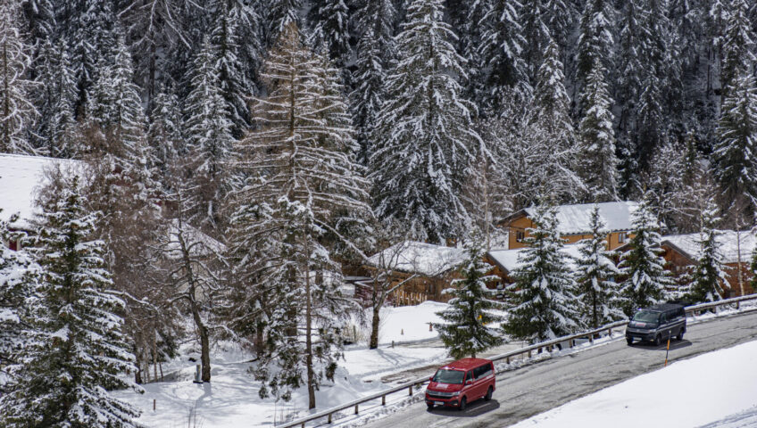 Two VW vans driving through a ski resort