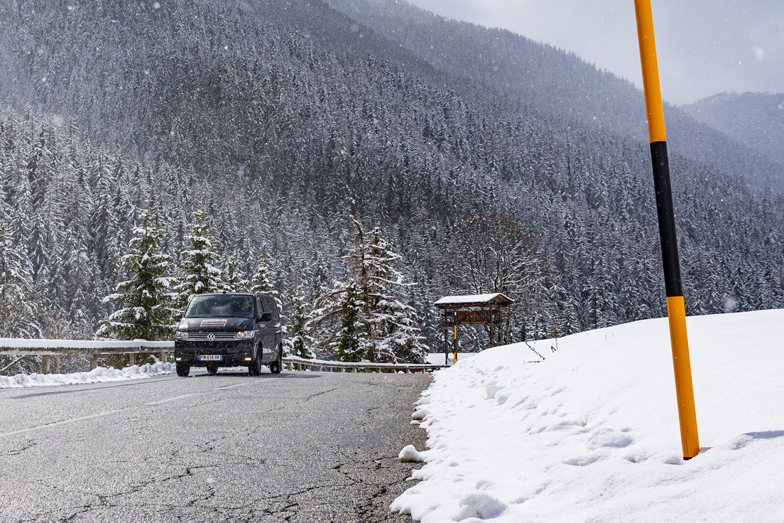 Black VW ski transfer van driving on mountain road