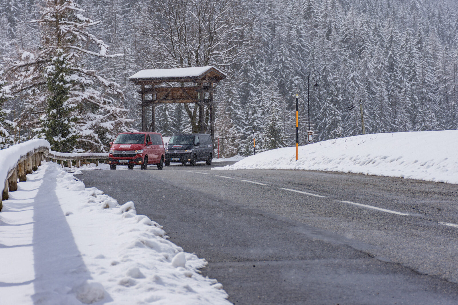snowy road in mountains with two VW vans driving to a ski resort