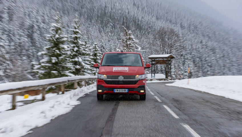 red van zooming towards camera on snowy mountain road