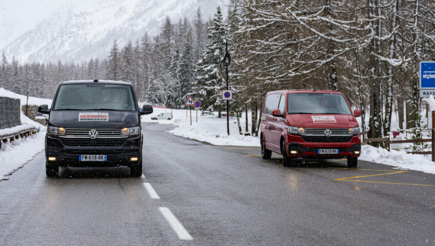 Black and white van parking on road with snow
