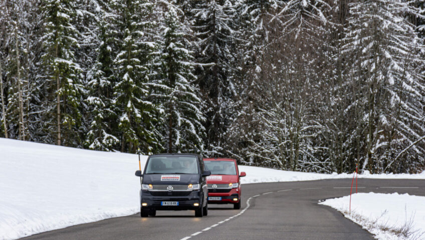 Two ski transfer vans driving on mountain road very close together