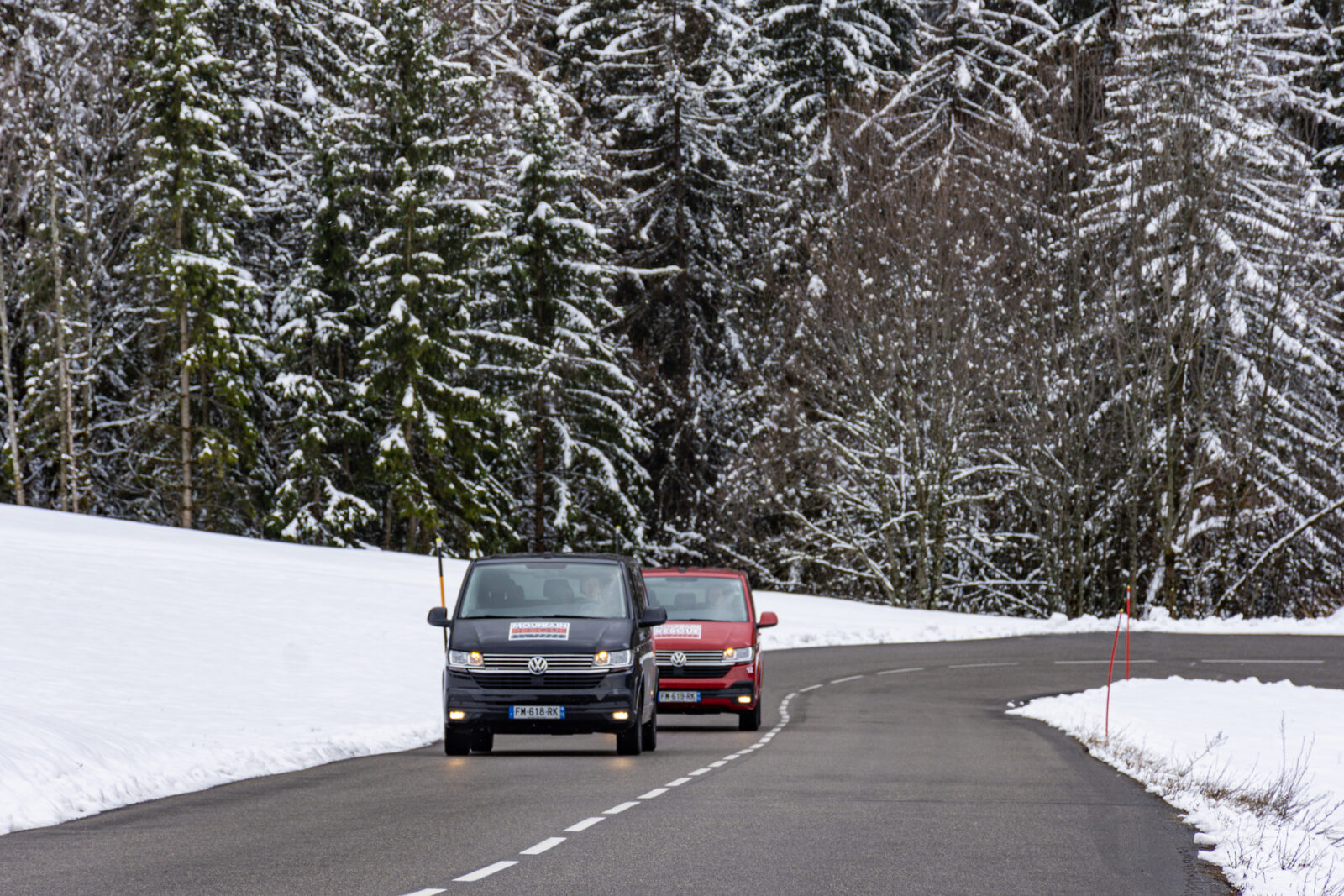 Two ski transfer vans driving on mountain road very close together