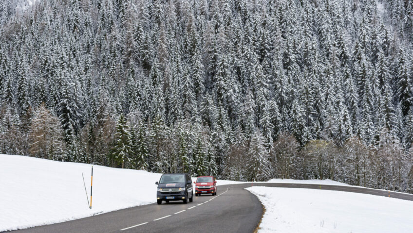 2 VW vans on mountain road with snow covering around them