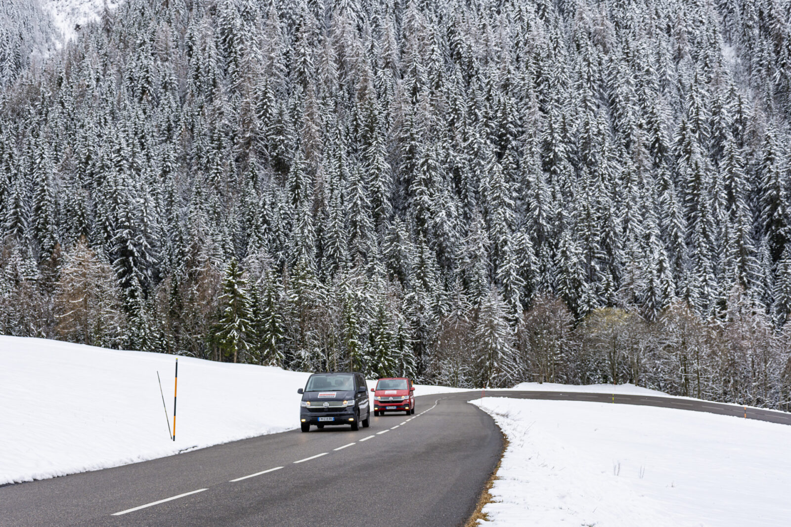 2 VW vans on mountain road with snow covering around them
