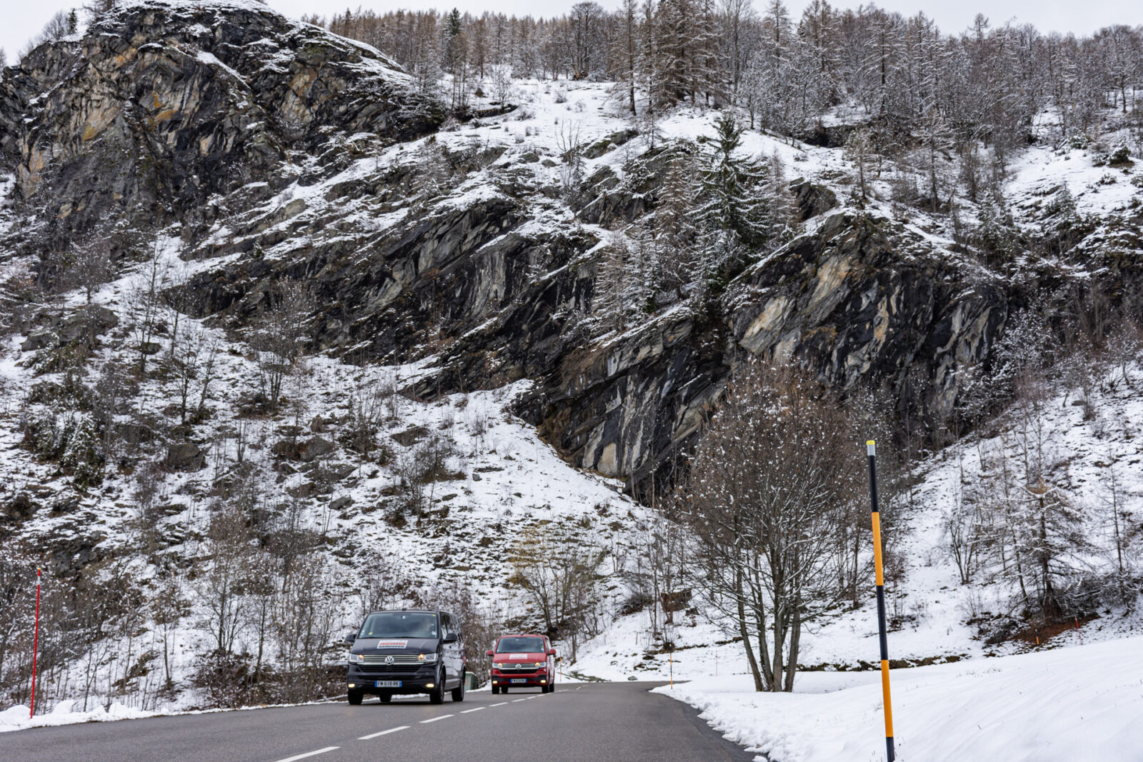 Two Mountain Rescue Transfer vans on a road with tall mountains behind them.