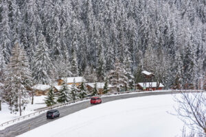 Red and black ski transfer vans driving through an alpine village